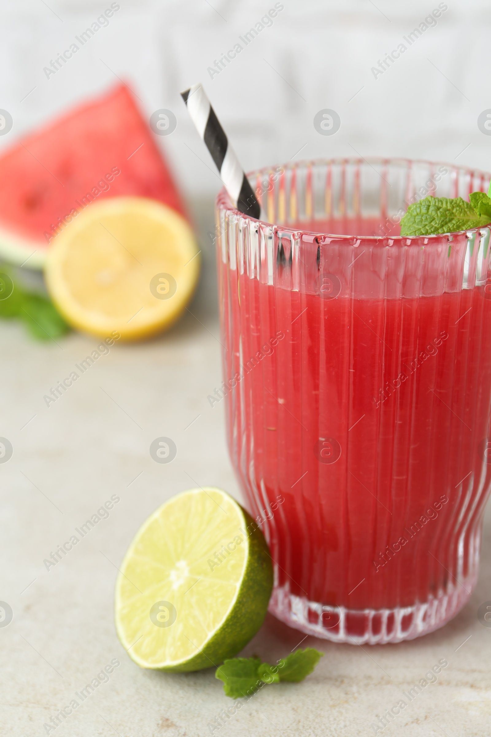 Photo of Delicious watermelon drink in glass, fresh fruits and mint on light table, closeup