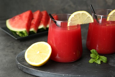 Photo of Delicious watermelon drink in glasses, fresh fruits and mint on grey table, closeup