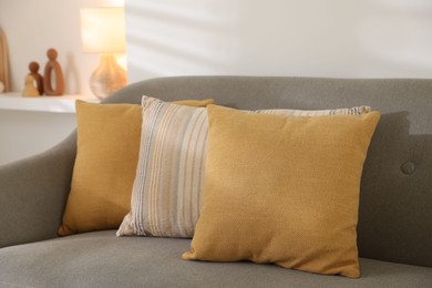 Photo of Different soft pillows on gray sofa in living room