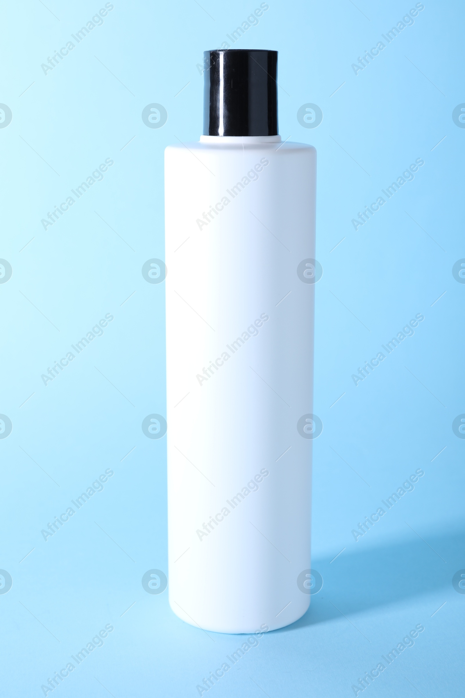 Photo of Shampoo in bottle on light blue background. Personal care product