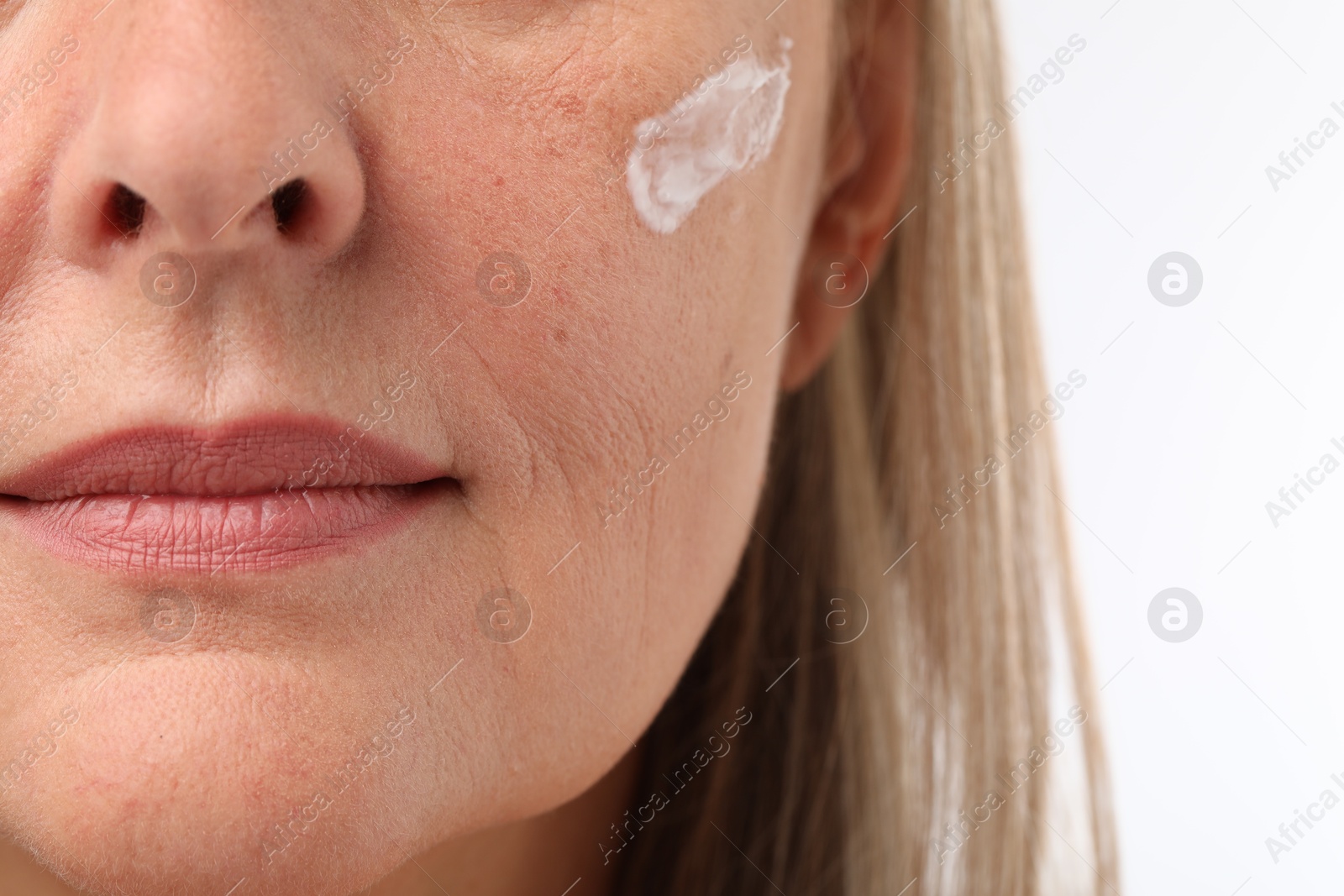 Photo of Senior woman with face cream on white background, closeup