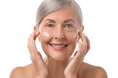 Photo of Senior woman with face cream on white background