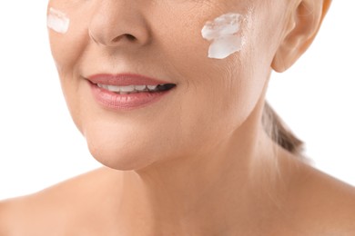 Photo of Senior woman with face cream on white background, closeup