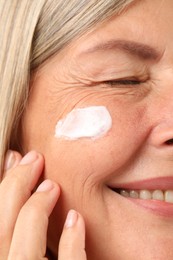 Senior woman with cream on face, closeup