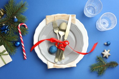 Photo of Beautiful Christmas setting with plates, elegant cutlery and festive decor on blue table, flat lay