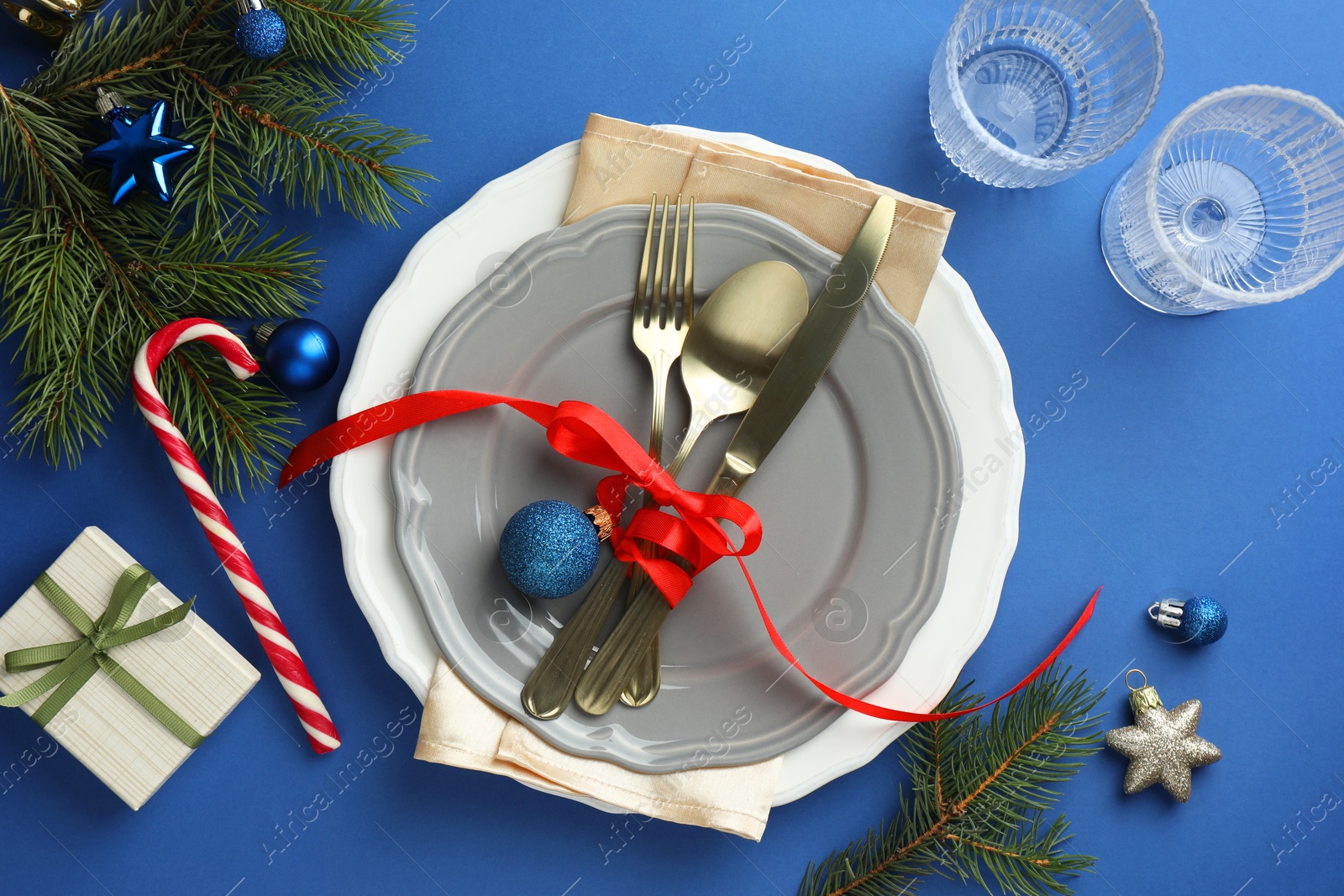 Photo of Beautiful Christmas setting with plates, elegant cutlery and festive decor on blue table, flat lay