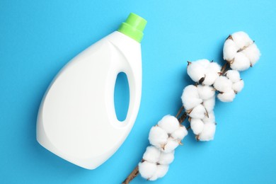 Bottle of laundry detergent and cotton flowers on blue background, flat lay