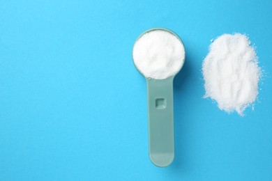 Measuring scoop with laundry powder on blue background, flat lay. Space for text