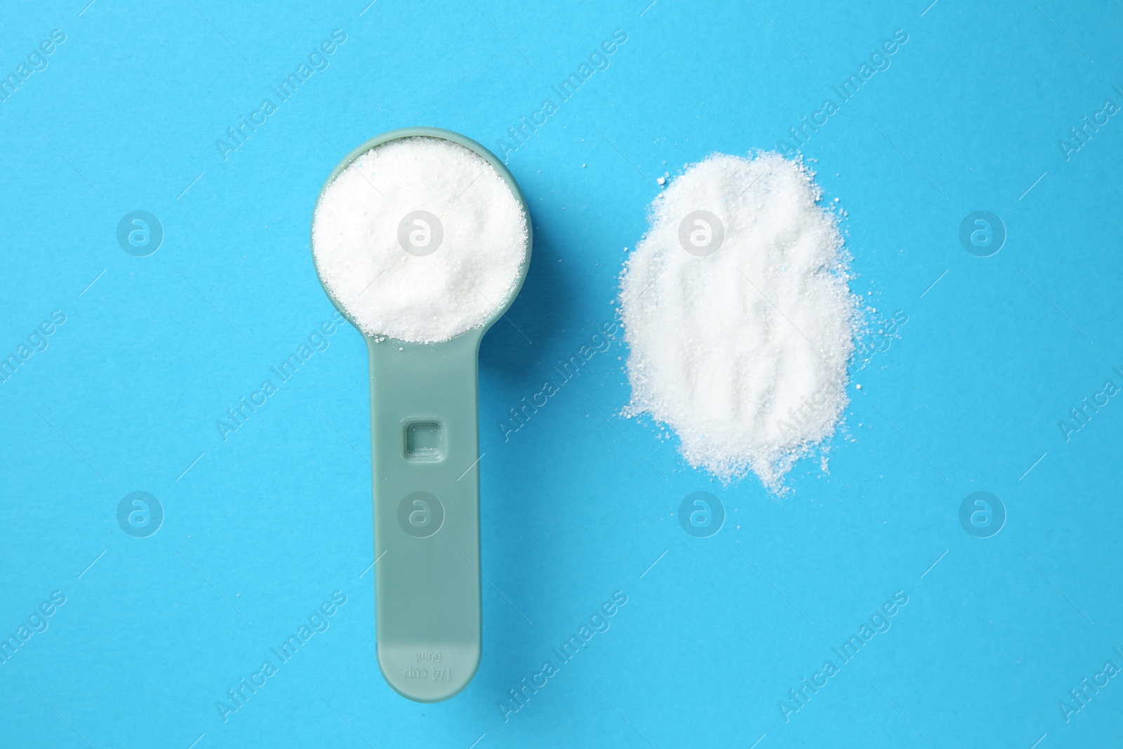 Photo of Measuring scoop with laundry powder on blue background, flat lay