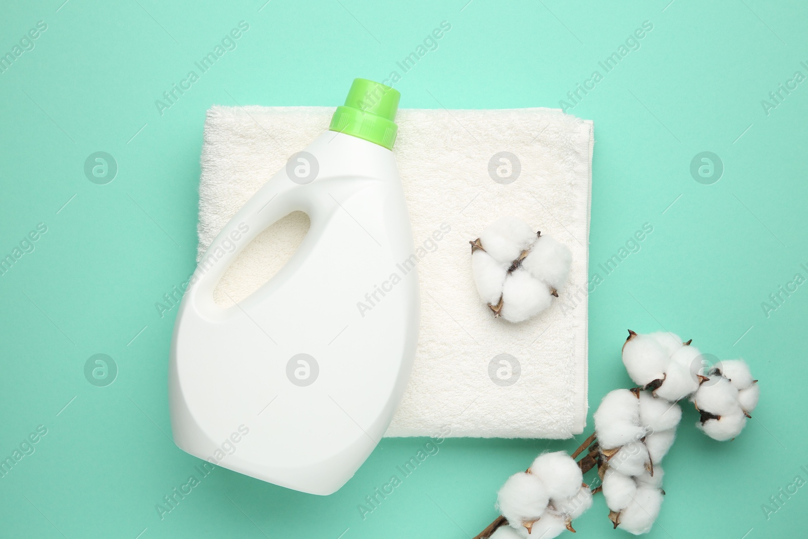 Photo of Bottle of laundry detergent, towel and cotton flowers on turquoise background, flat lay