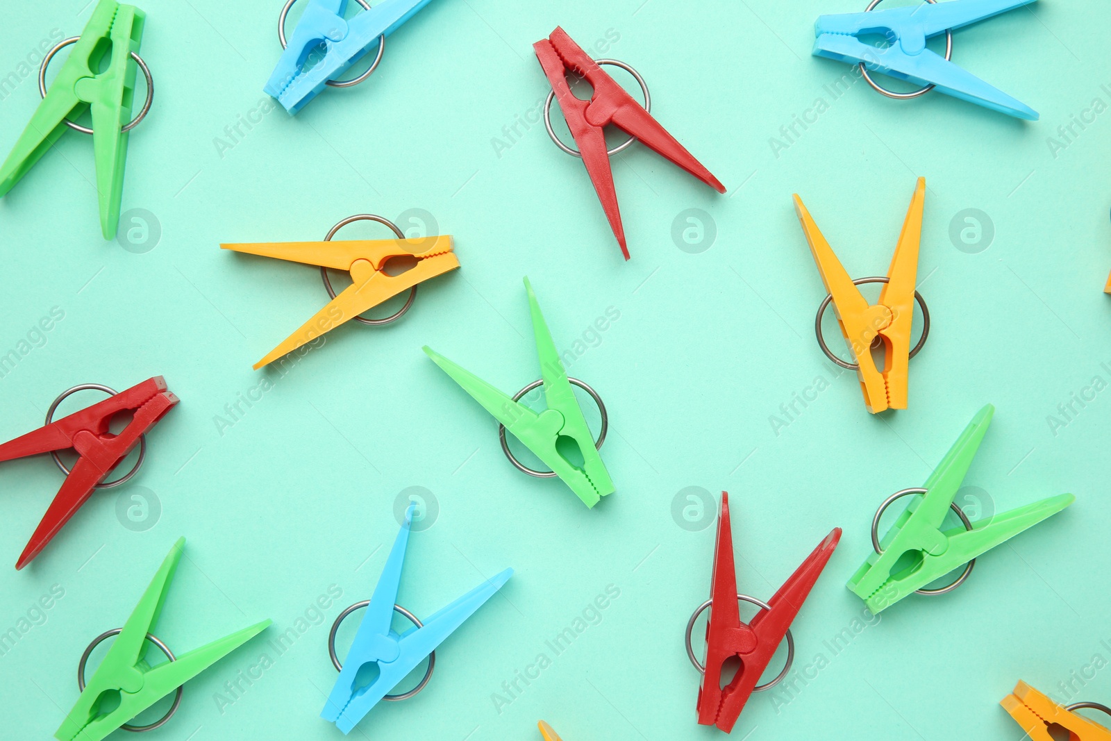 Photo of Many colorful clothespins on turquoise background, flat lay