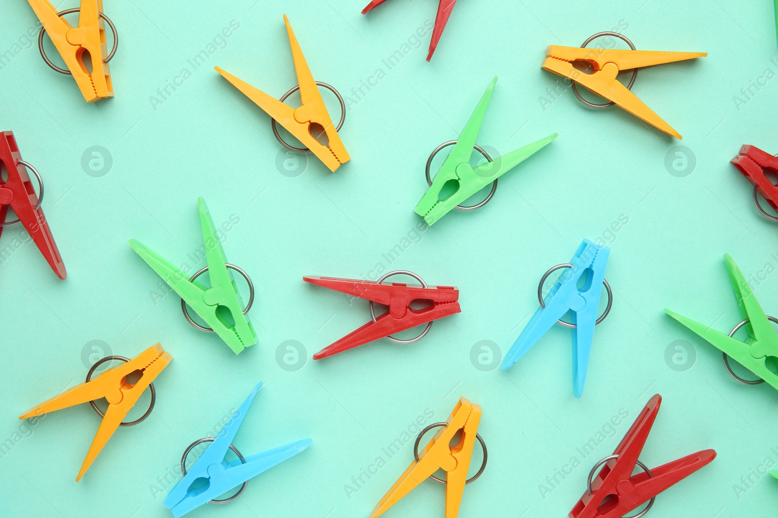 Photo of Many colorful clothespins on turquoise background, flat lay