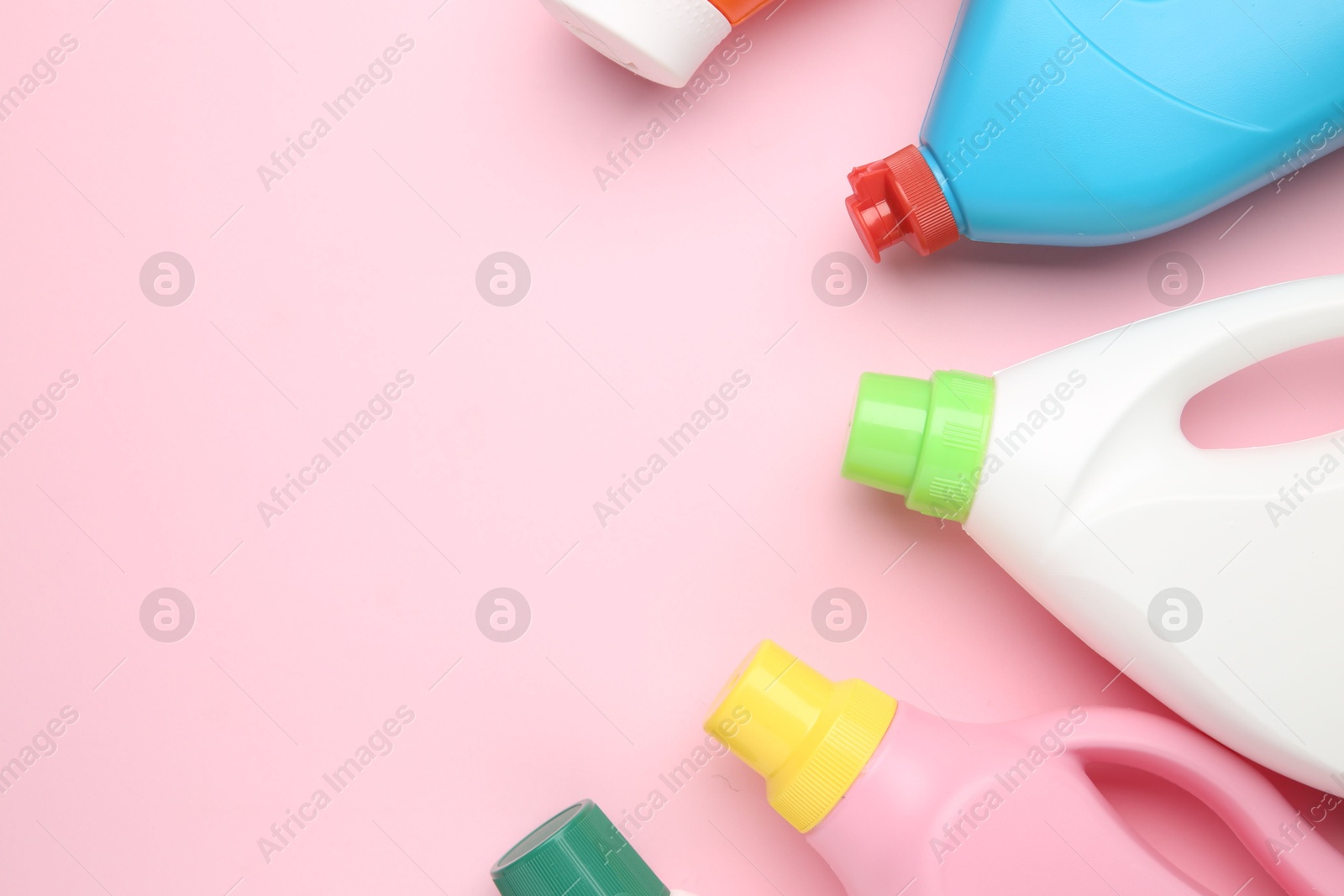 Photo of Bottles of different laundry detergents on pink background, top view. Space for text