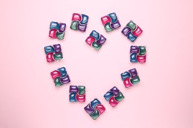 Photo of Heart made of laundry detergent pods on pink background, flat lay