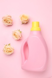 Photo of Bottle of laundry detergent and flowers on pink background, closeup