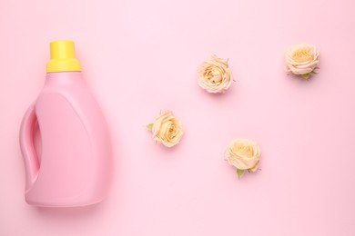 Photo of Bottle of laundry detergent and flowers on pink background, closeup