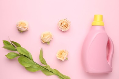 Photo of Bottle of laundry detergent and flowers on pink background, closeup