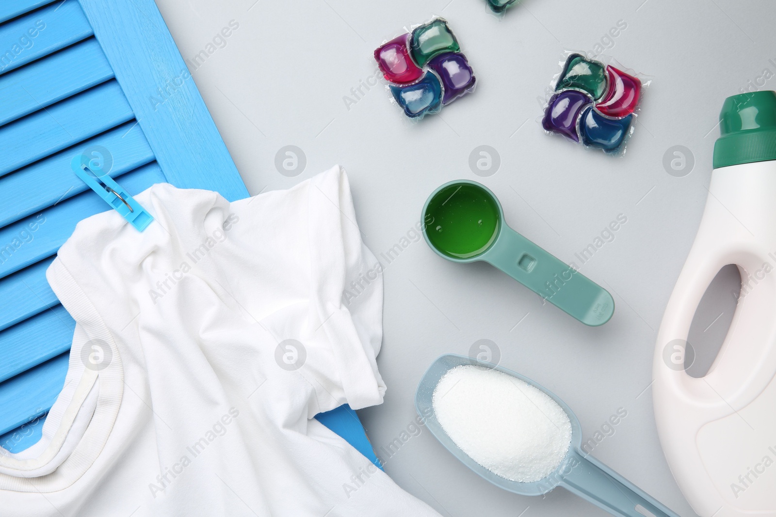 Photo of Different laundry detergents and t-shirt on grey background, flat lay