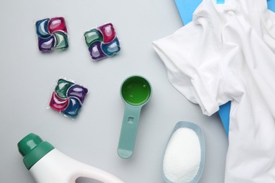 Photo of Different laundry detergents and t-shirt on grey background, flat lay