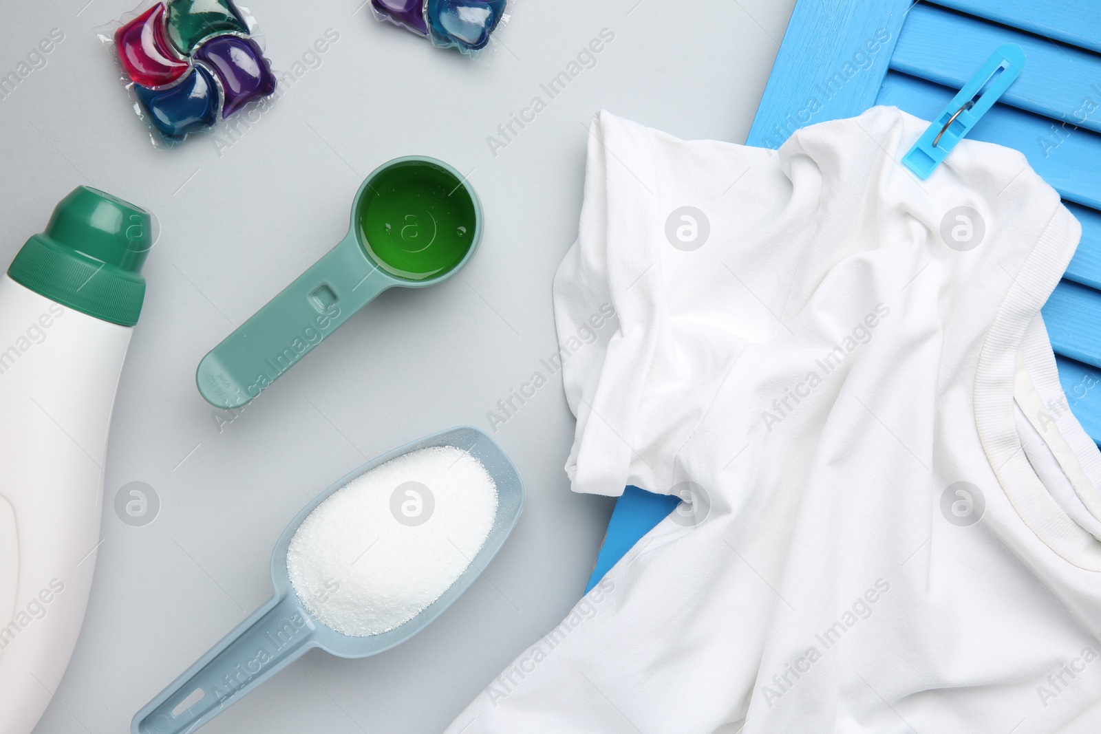 Photo of Different laundry detergents and t-shirt on grey background, flat lay