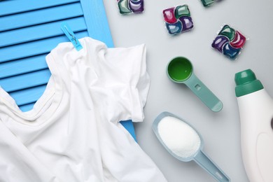 Photo of Different laundry detergents and t-shirt on grey background, flat lay