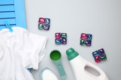 Photo of Different laundry detergents and t-shirt on grey background, flat lay