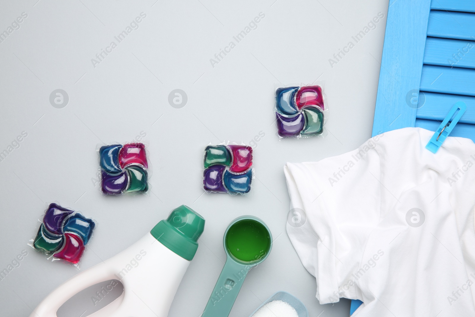 Photo of Different laundry detergents and t-shirt on grey background, flat lay. Space for text