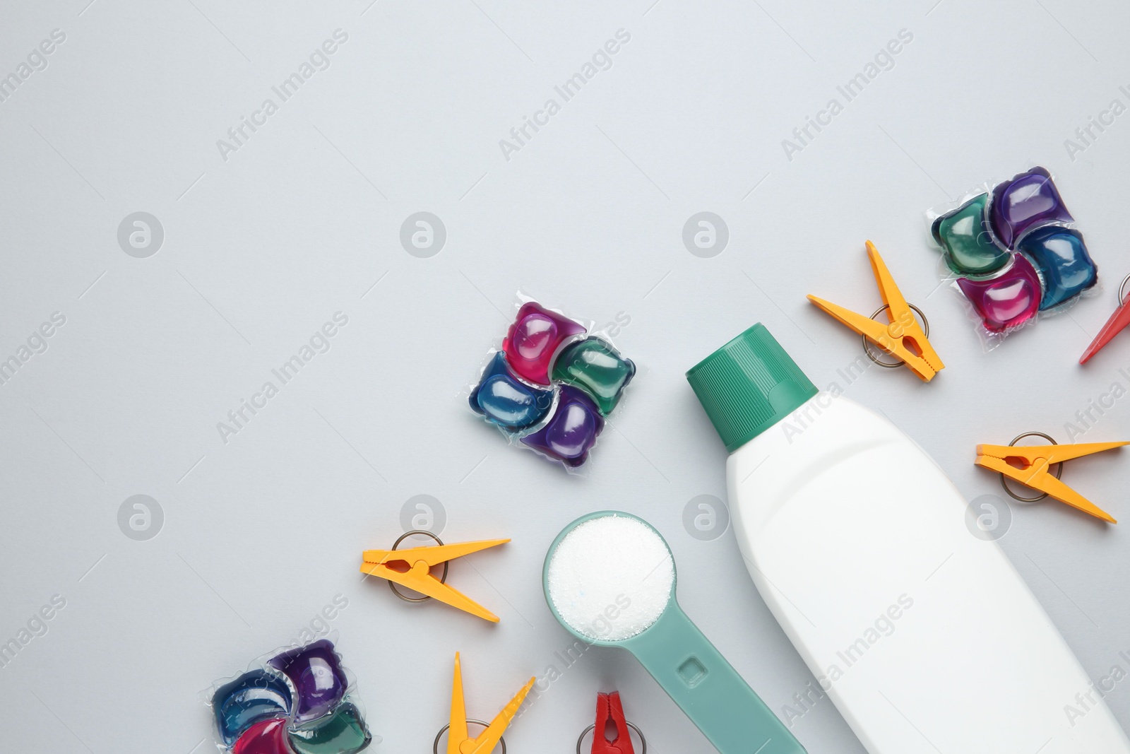 Photo of Different laundry detergents and clothespins on grey background, flat lay. Space for text