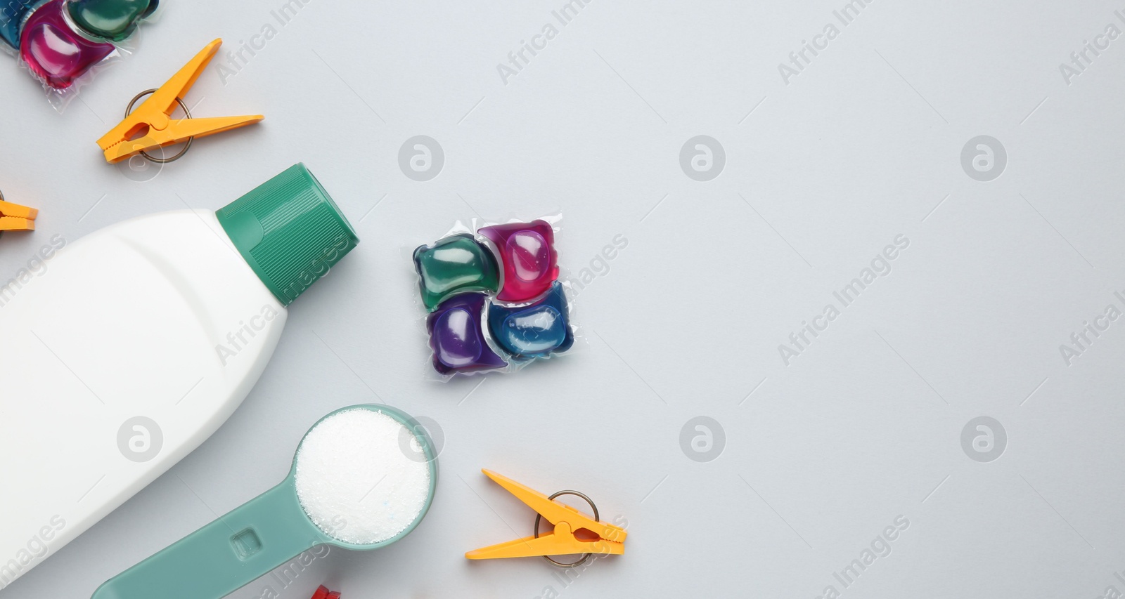 Photo of Different laundry detergents and clothespins on grey background, flat lay. Space for text