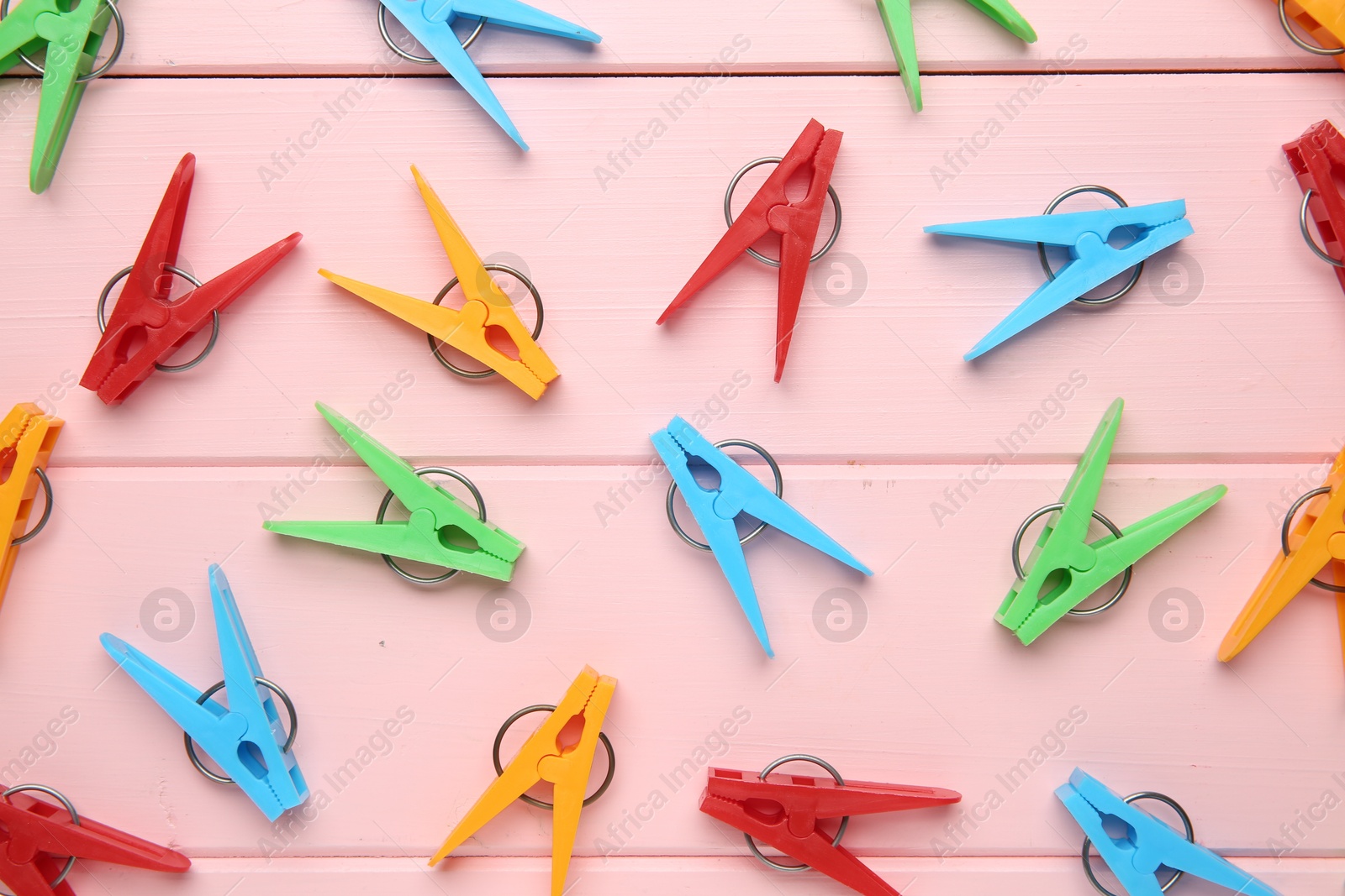 Photo of Many bright clothespins on pink wooden table, flat lay