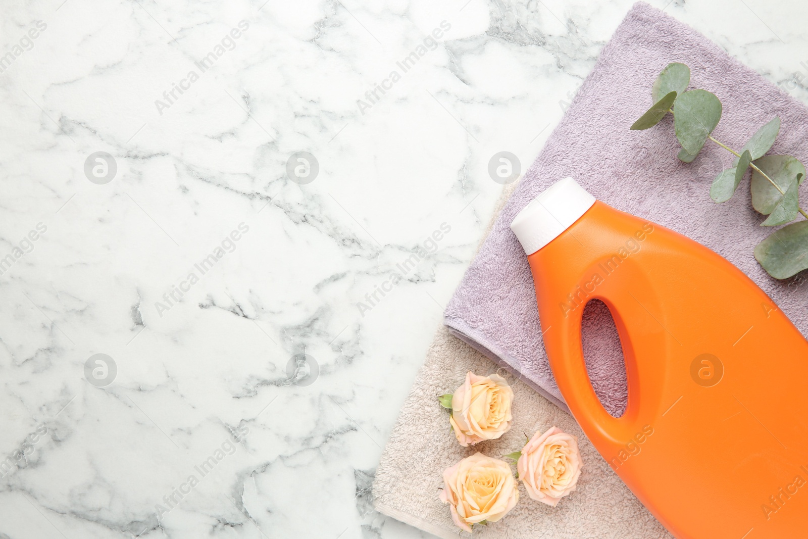 Photo of Laundry detergent in bottle, rose flowers, eucalyptus branches and towels on white marble table, top view. Space for text