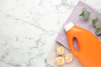 Photo of Laundry detergent in bottle, rose flowers, eucalyptus branches and towels on white marble table, top view. Space for text