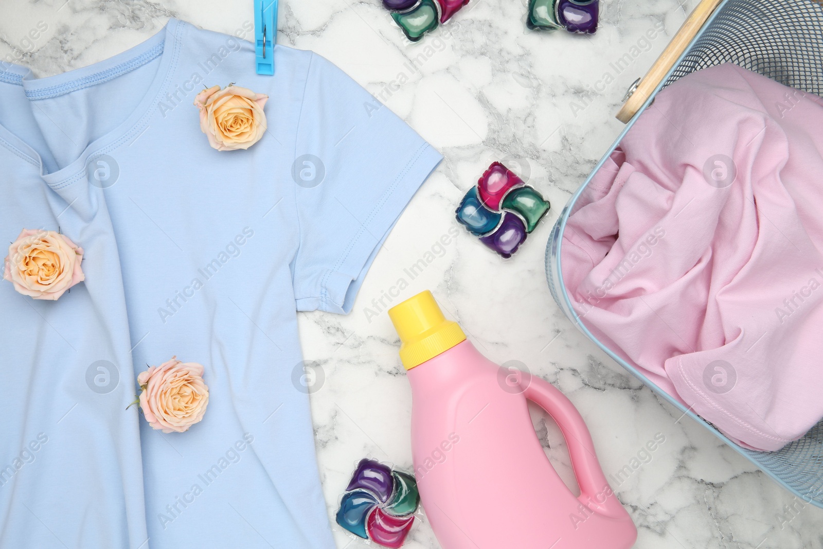 Photo of Flat lay composition with laundry detergents, rose flowers and t-shirts on white marble table