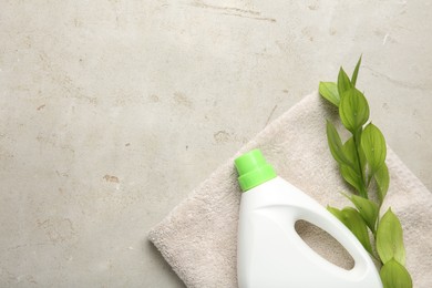 Photo of Laundry detergent in bottle, branch and towel on grey textured table, top view. Space for text