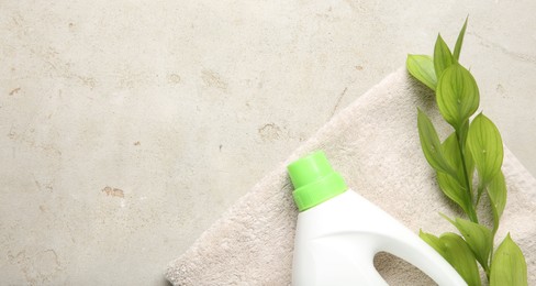 Photo of Laundry detergent in bottle, branch and towel on grey textured table, top view. Space for text