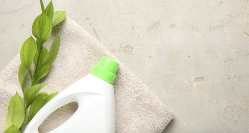 Photo of Laundry detergent in bottle, branch and towel on grey textured table, top view. Space for text