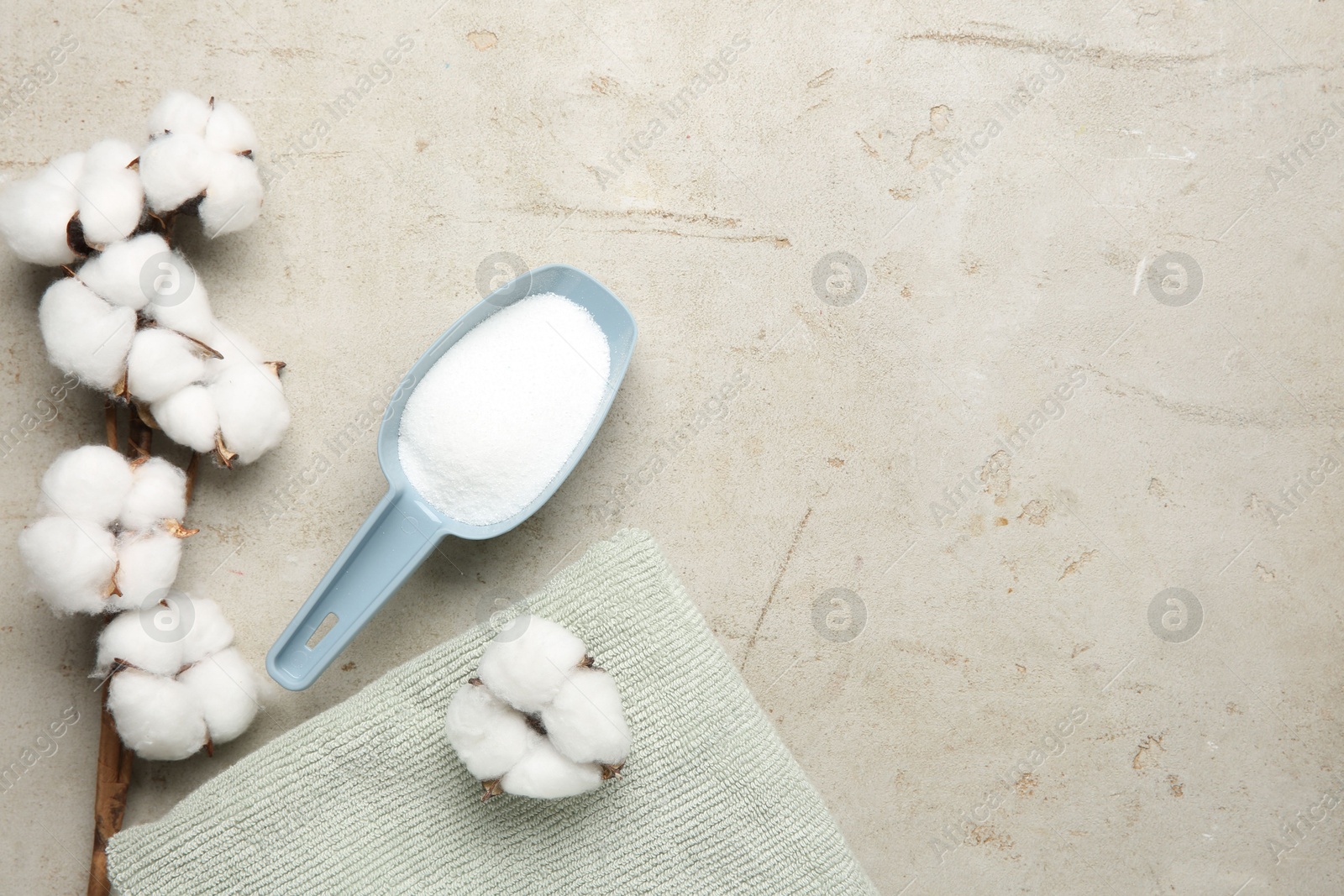 Photo of Scoop with laundry detergent, cotton flowers and towel on grey textured table, flat lay. Space for text