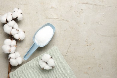 Photo of Scoop with laundry detergent, cotton flowers and towel on grey textured table, flat lay. Space for text