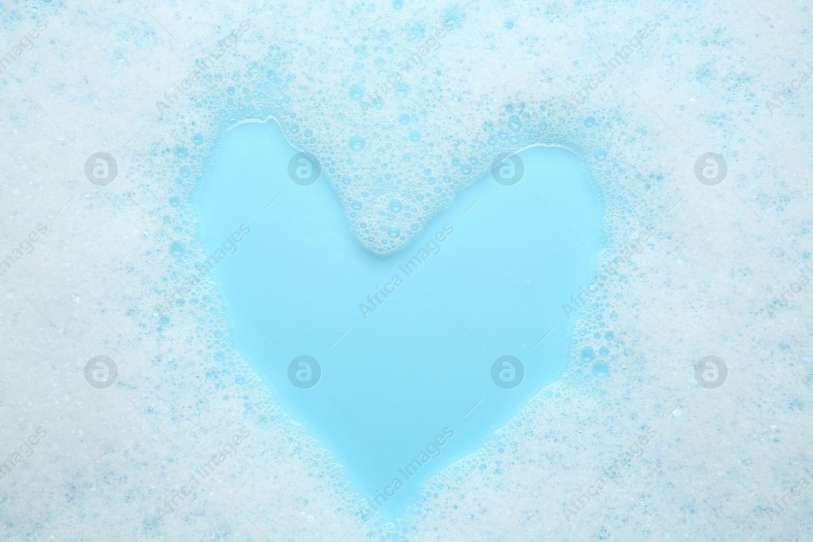 Photo of Washing laundry. White foam with bubbles on light blue background, top view