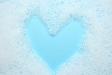 Photo of Washing laundry. White foam with bubbles on light blue background, top view