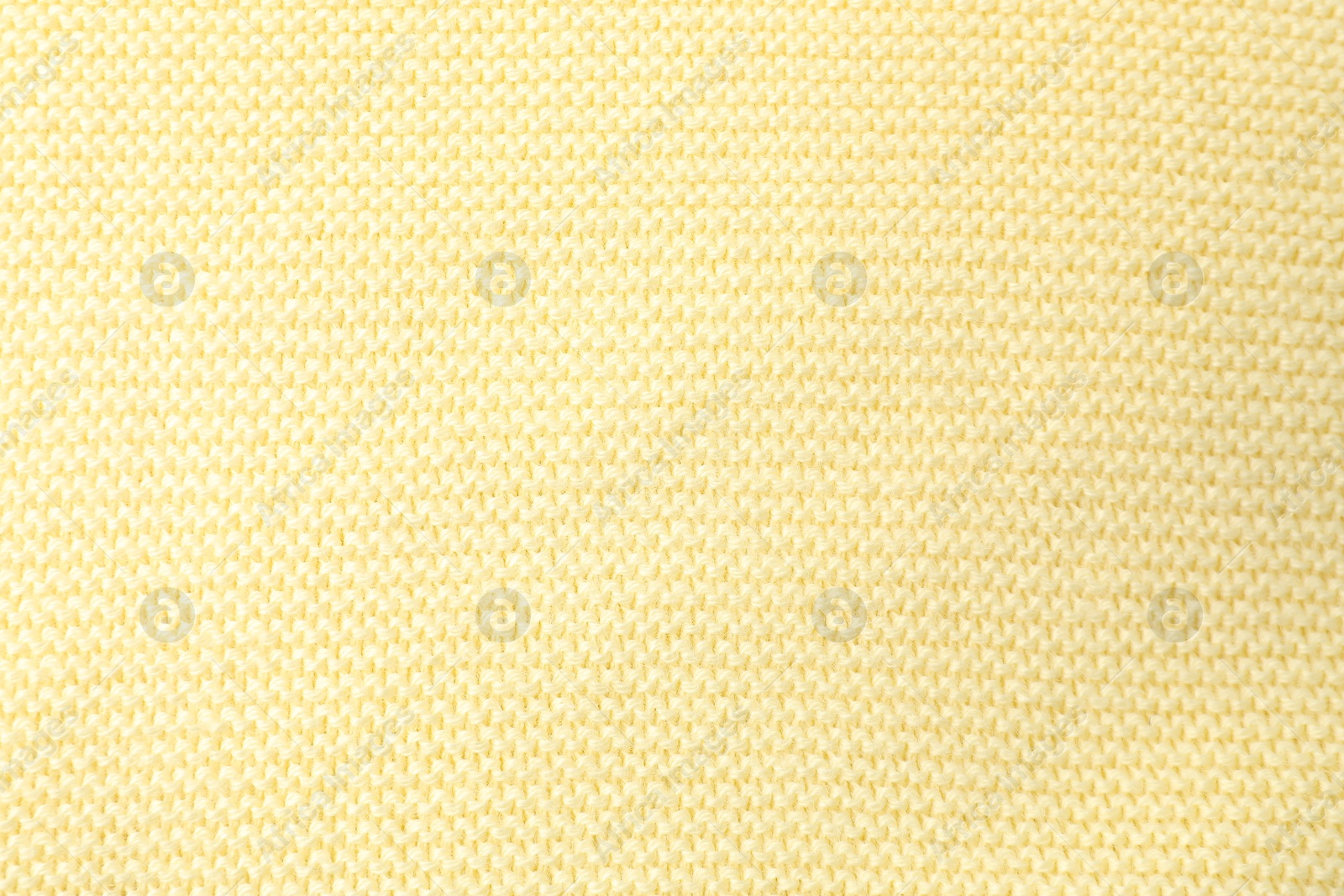 Photo of Texture of light yellow knitted fabric as background, top view