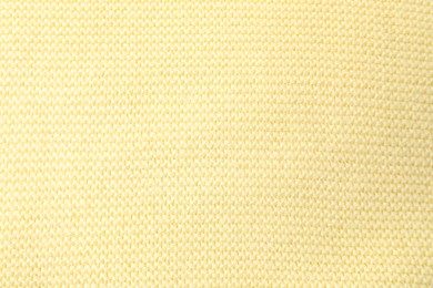 Photo of Texture of light yellow knitted fabric as background, top view