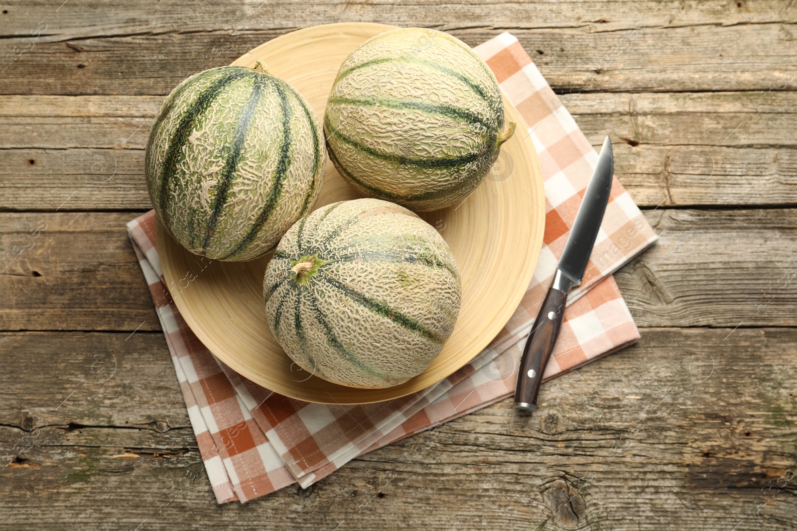 Photo of Ripe Cantaloupe melons and knife on wooden table, flat lay