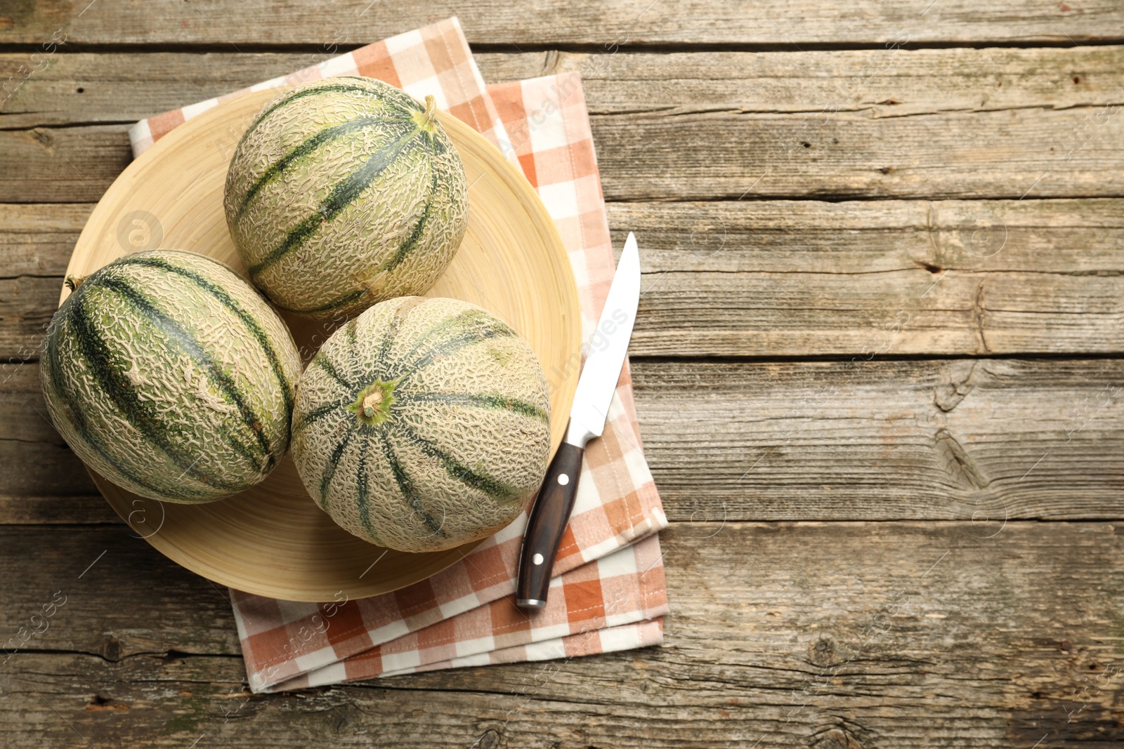 Photo of Ripe Cantaloupe melons and knife on wooden table, flat lay. Space for text