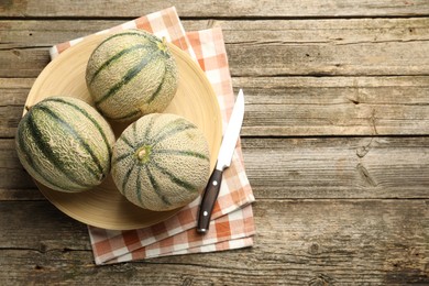 Ripe Cantaloupe melons and knife on wooden table, flat lay. Space for text