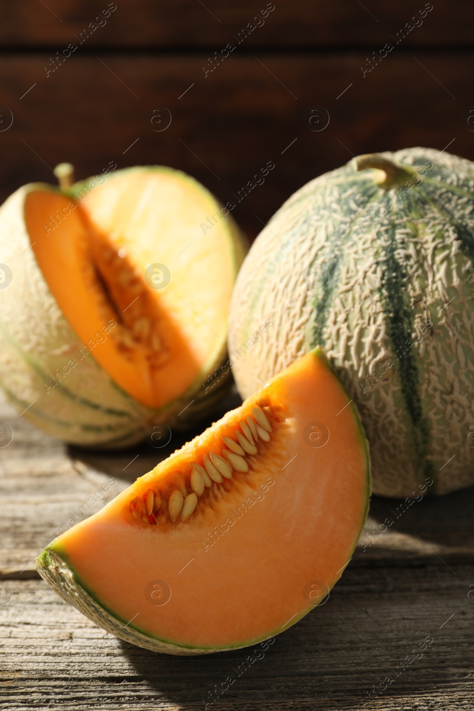 Photo of Whole and cut ripe Cantaloupe melons on wooden table, closeup