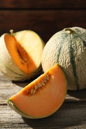 Whole and cut ripe Cantaloupe melons on wooden table, closeup