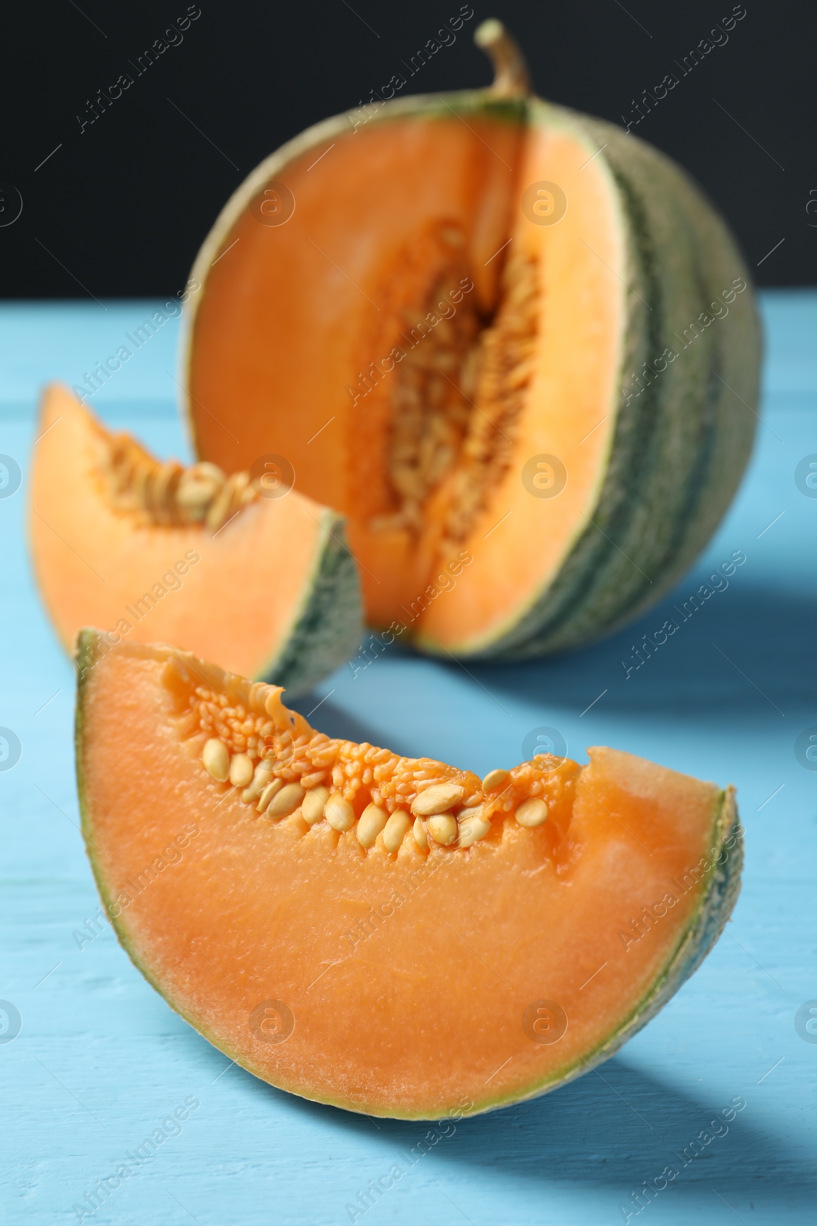 Photo of Cut ripe Cantaloupe melon on light blue wooden table, closeup