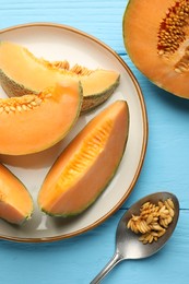 Photo of Cut ripe Cantaloupe melon and spoon with seeds on light blue wooden table, flat lay