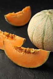 Photo of Cut and whole ripe Cantaloupe melons on dark textured table, closeup